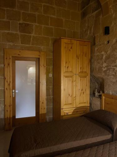 a bedroom with a bed and a wooden cabinet at '19, Kenn L-Istorja' A remarkable 500 years old house of character in Senglea