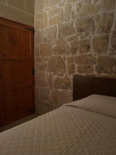 a bed in a room with a stone wall at '19, Kenn L-Istorja' A remarkable 500 years old house of character in Senglea