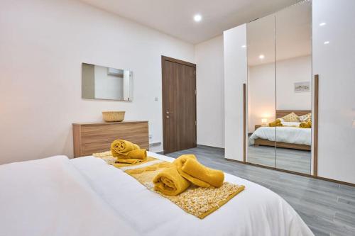 Un dormitorio con una cama con toallas amarillas. en Two Bedroom Apartment in Xemxija, St. Paul's Bay en St. Paul's Bay