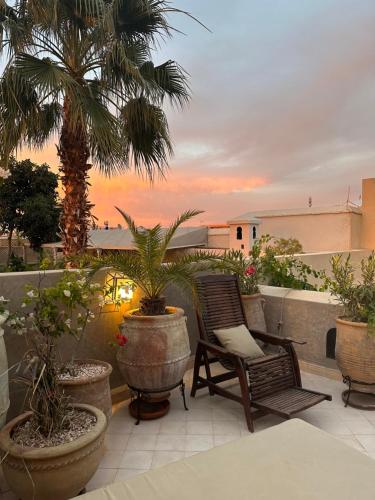 un patio con una silla, palmeras y una puesta de sol en Riad des Fragrances dar el Bacha en Marrakech