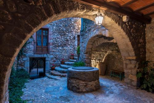 un edificio in pietra con arco e sgabello al centro di Hostal Can Xicu a Capmany