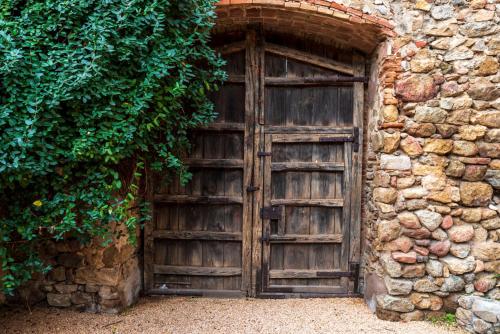 stare drewniane drzwi w kamiennej ścianie w obiekcie Hostal Can Xicu w mieście Capmany