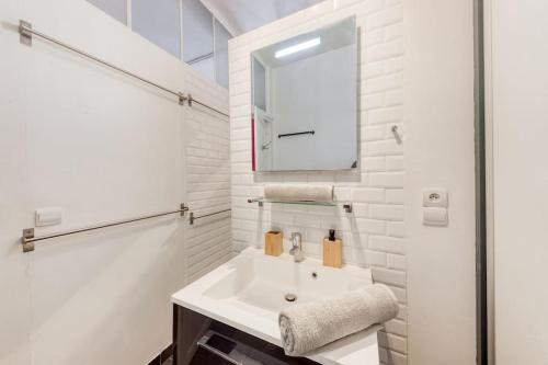 een witte badkamer met een wastafel en een spiegel bij « La cour royale » appartement prestigieux à 50m du château de Versailles in Versailles