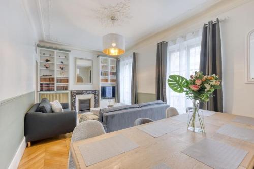 un salon avec une table avec un vase de fleurs dans l'établissement « La cour royale » appartement prestigieux à 50m du château de Versailles, à Versailles