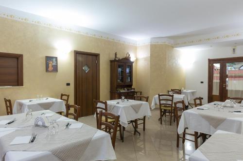 uma sala de jantar com mesas e cadeiras com toalhas de mesa brancas em B&B Spanò em Polistena