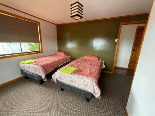 a room with two beds and a window at Posada De Los Gatos in Puerto Natales