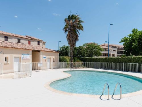 - une piscine avec un palmier à côté d'un bâtiment dans l'établissement Pavillon 5 pièces avec piscine, terrasse et WIFI - 8 pers, Narbonne-Plage - FR-1-409-28, à Narbonne