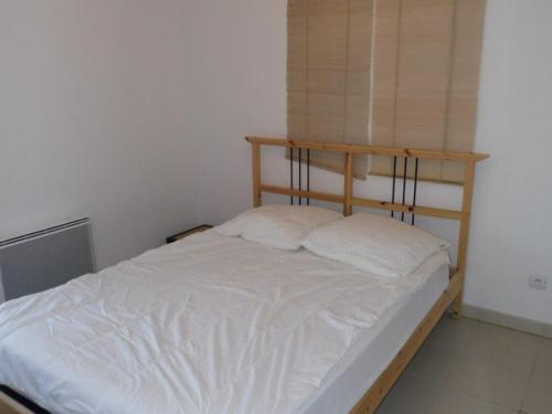 Cette petite chambre comprend un lit avec des draps blancs. dans l'établissement Appartement cosy 2 pièces avec accès direct plage, piscine et parking privé à Marseillan - FR-1-326-512, à Marseillan