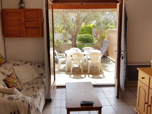 un salon avec un canapé, une table et des chaises dans l'établissement Pavillon cosy avec terrasse, 5 couchages, proche plage et nature, animaux bienvenus - FR-1-409-95, à Narbonne-Plage