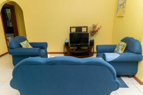 sala de estar con 2 sillas azules y TV en Bougainvillea Apartments, en Castries