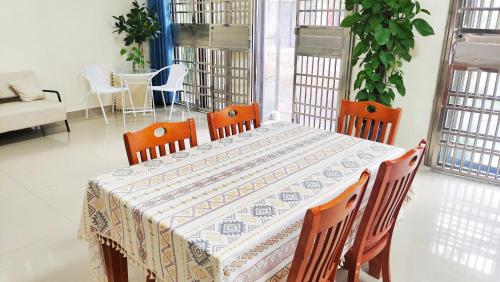a dining room table with chairs and a tablecloth on it at 闲肆民宿 in Sanya