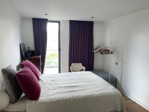 Un dormitorio con una cama con almohadas moradas y una ventana en Bienvenue chez Juliette, en Bruselas