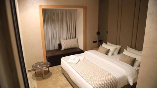 um quarto com uma cama branca e uma cadeira em MH HOTEL LA CASA em El Aiune
