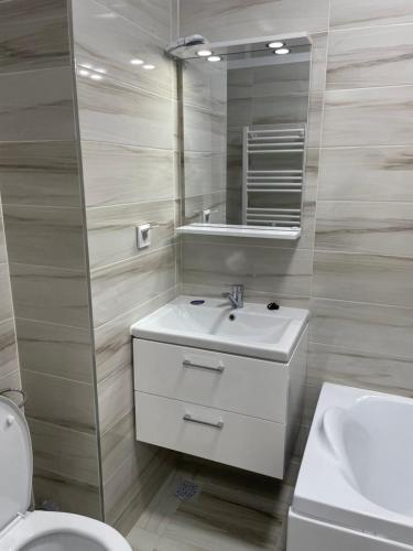een badkamer met een wastafel, een toilet en een spiegel bij Bucium Comfort Apartaments in Iaşi