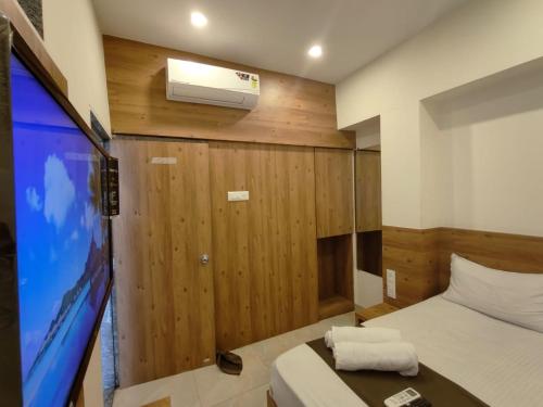 a room with a bed and a large screen tv at Hotel Apple Inn - Santacruz in Mumbai