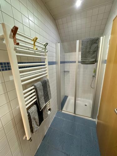 a white tiled bathroom with a shower and towels at Gemütliches Appartement - WBS in Goldkronach