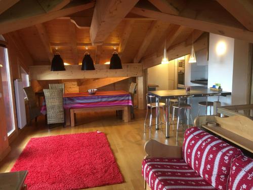 a living room with a table and a red rug at les 7 laux immobilier chalet C in Prapoutel