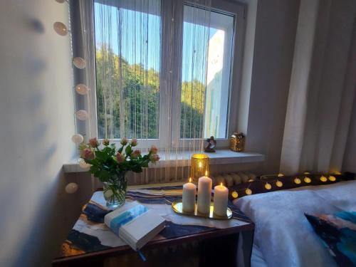 een slaapkamer met een bed met kaarsen en een raam bij Apartament Kolberga II in Sopot