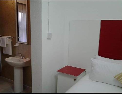 a bathroom with a bed with a sink and a mirror at Keeme-Nao Self Catering Apartments in Gaborone