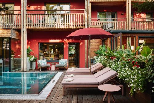 a patio with a table and an umbrella and a pool at Small Luxury Hotel of the World - DasPosthotel in Zell am Ziller