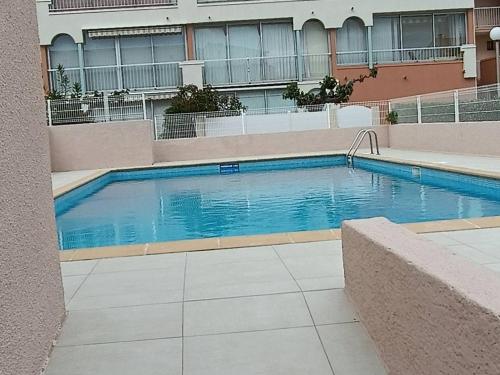 une grande piscine devant un immeuble dans l'établissement Appartement rénové près de la plage Richelieu avec piscine, garage et vélos fournis - FR-1-723-113, au Cap d'Agde