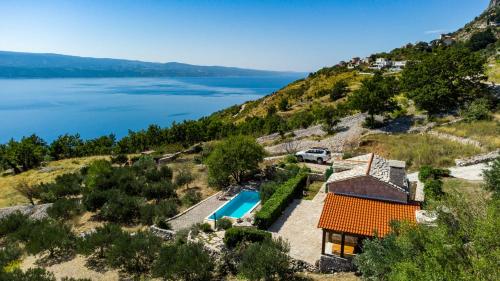 an aerial view of a house on a hill with a lake at Dalmatian stone villa with heated pool in Lokva Rogoznica