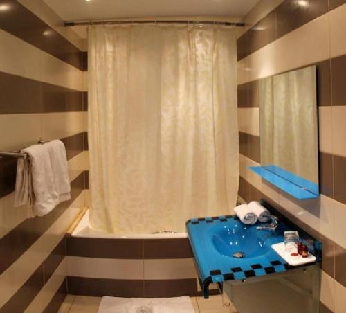 a bathroom with a blue sink and a tub at HOTEL IKRAM EL DHAYF in El Madania