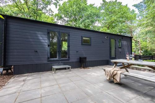 a black cabin with a picnic table in front of it at Prachtig chalet in de bossen in Nunspeet