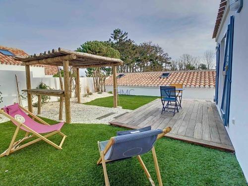 a backyard with a deck with chairs and an umbrella at La Tranquillité in LʼHerbaudière