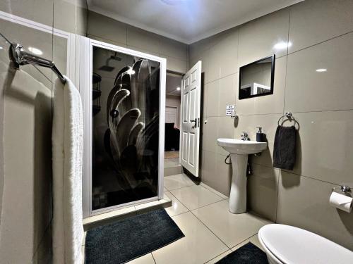 a bathroom with a shower and a sink and a toilet at Lincoln Moon Guesthouse in Graskop