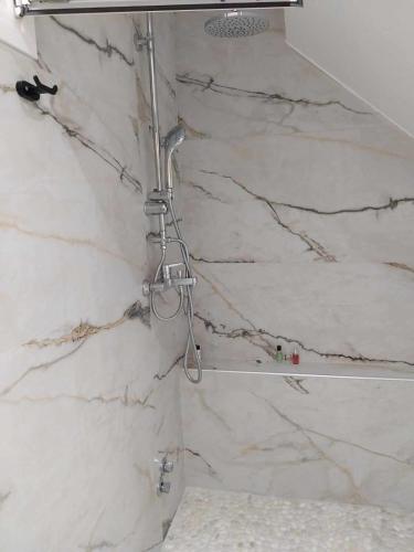 a shower in a bathroom with white marble walls at Galazio Seaside Luxury Rooms & Coffee Shop in Platamonas