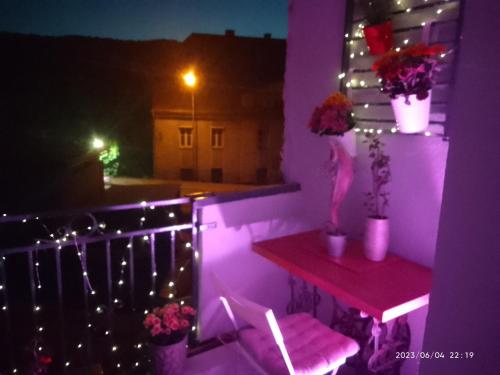 Habitación púrpura con balcón con mesa y flores en Apartament Centrum Nowa Ruda, en Nowa Ruda