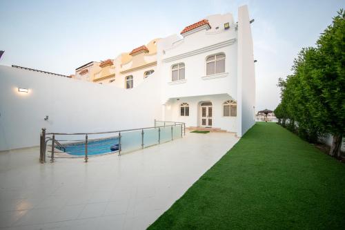a large white building with a green lawn at Blue Star Villa in Durat Alarous