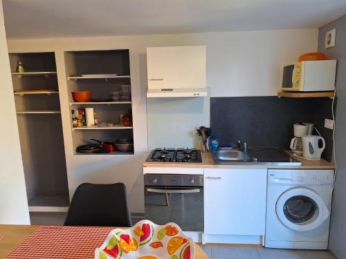 a small kitchen with a stove and a washing machine at Agréable Studio tout équipé in Montsoué