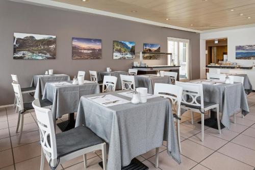 a dining room with tables and white chairs at Hotel Du Lac in Locarno