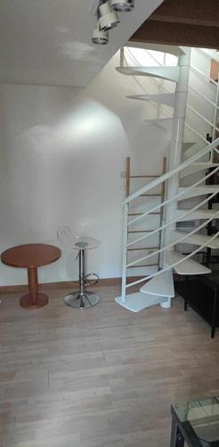 - un escalier en colimaçon dans une pièce avec une table et un tabouret dans l'établissement Bail Mobilité Duplex Cottage, à Châtillon
