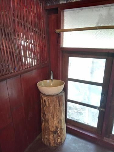 łazienka z umywalką na pniu drzewa obok okna w obiekcie Room 2 w mieście Ban Tham