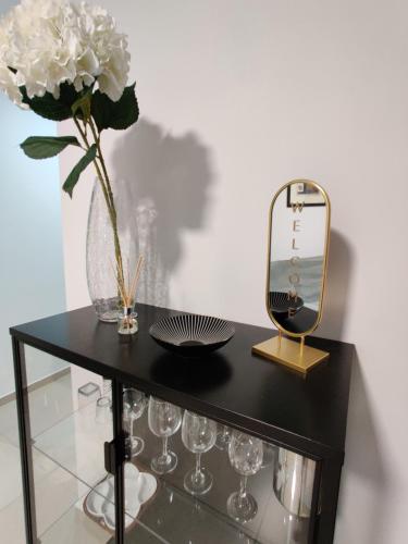 een zwarte tafel met een vaas met bloemen en een spiegel bij DePiro Point Deluxe - Sliema Holiday Rental in Sliema