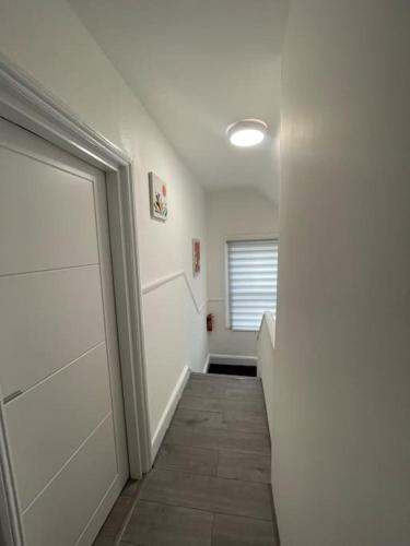 pusty korytarz z drzwiami i oknem w obiekcie Opal - Executive London Flat w mieście South Norwood