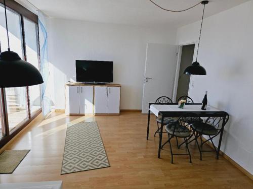 a living room with a table and chairs and a television at Seeblick in Daisendorf
