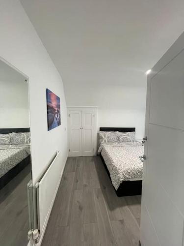 biały pokój z 2 łóżkami i korytarzem w obiekcie Opal - Executive London Flat w mieście South Norwood