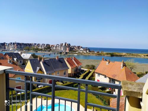 - un balcon offrant une vue sur les maisons et l'océan dans l'établissement DIVINE MARINA vue mer - Piscines, à Dives-sur-Mer