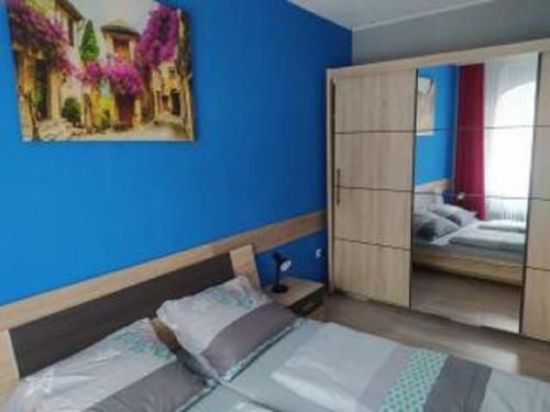 um quarto com uma cama e uma parede azul em Apartmán u Petrů 1 em Jáchymov