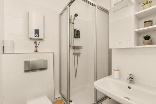 a white bathroom with a shower and a sink at FREE LIVING - City Design Apartments, Zentrum, Outlet, Balkon, Küche in Wolfsburg