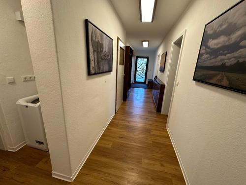 a hallway with white walls and wooden floors and paintings at Entspannung und Ruhe vor den Toren Berlins in Königs Wusterhausen