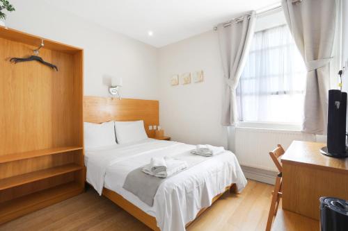 a bedroom with a bed with white sheets and a window at BeiRoom Hyde Park Apartments in London