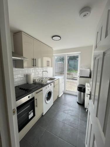 a white kitchen with a stove and a dishwasher at Citrine - Executive London Garden Flat in South Norwood
