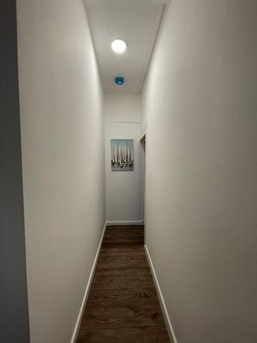 a hallway with white walls and a wooden floor at Citrine - Executive London Garden Flat in South Norwood