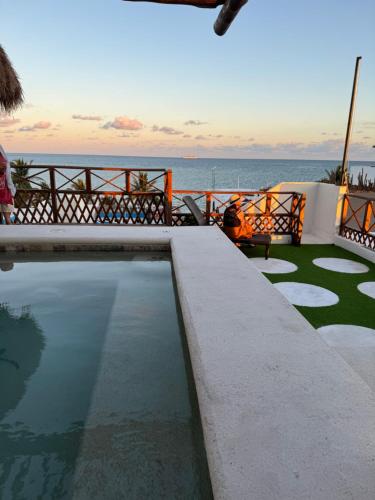 a swimming pool with the ocean in the background at Suites Valentina in Puerto Morelos