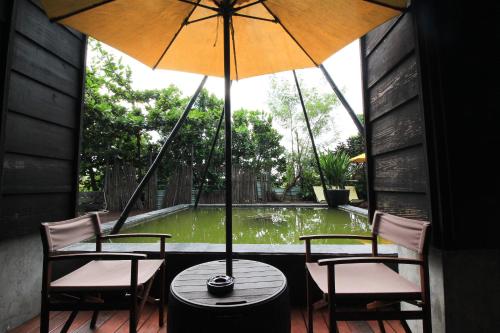 a table and chairs with an umbrella on a porch at Yellow House in Hengchun